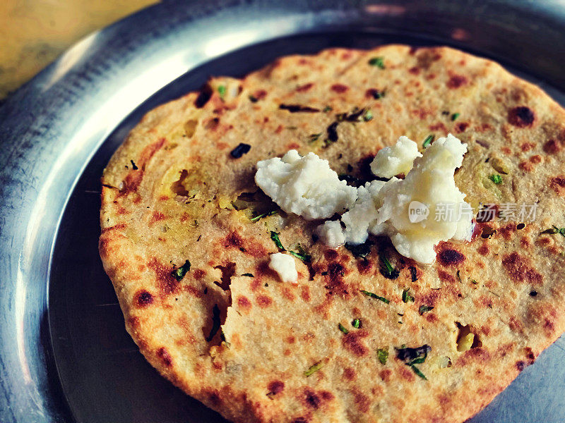 香脆的Amritsari Aloo-Paratha的水平点击，库尔查塞满了土豆，洋葱，绿色丹尼亚和香料与白黄油makkhan在一个钢盘或塔利。